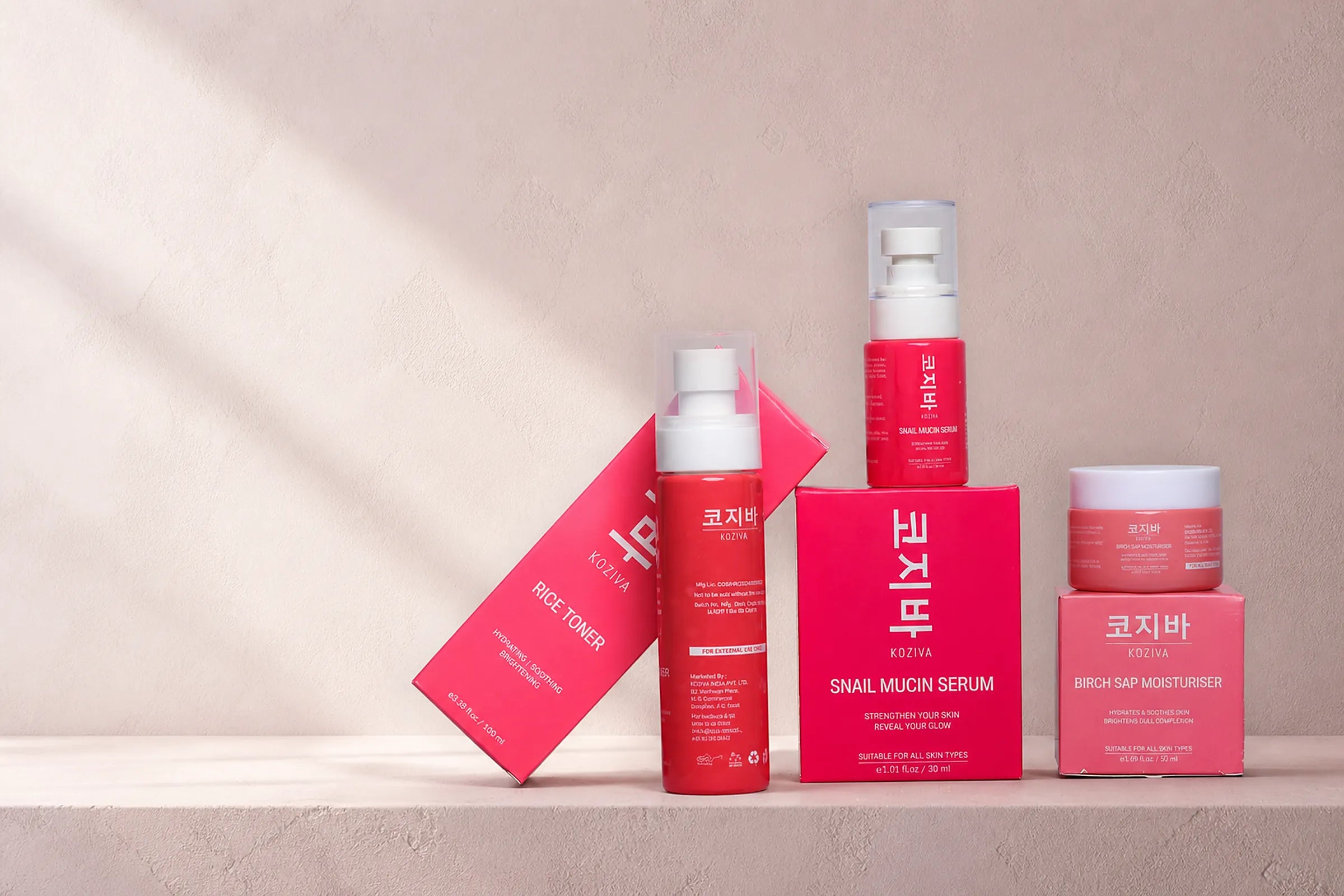 The full Koziva range with its cartons, arranged on a pink plaster ledge